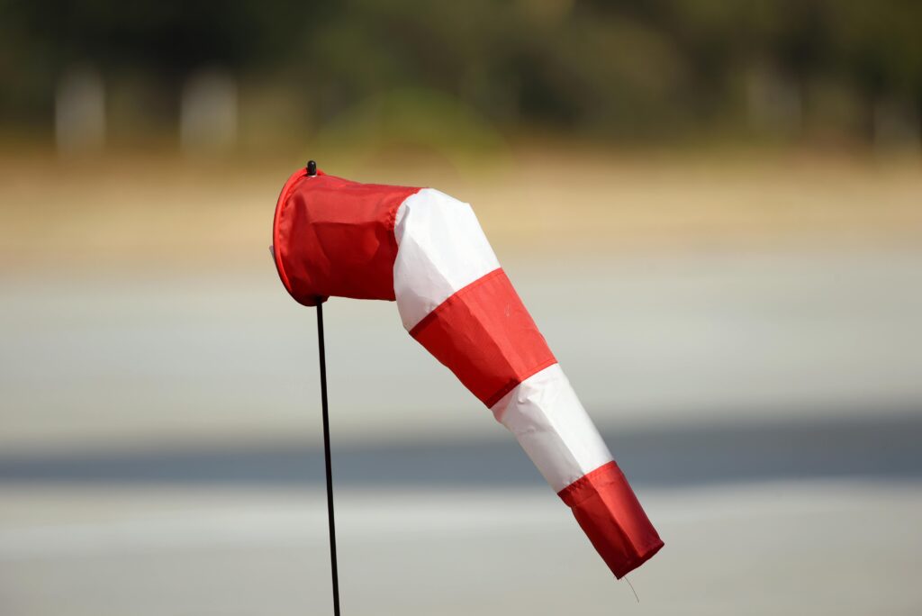 A red and white windsock indicating wind direction and strength on a clear day.