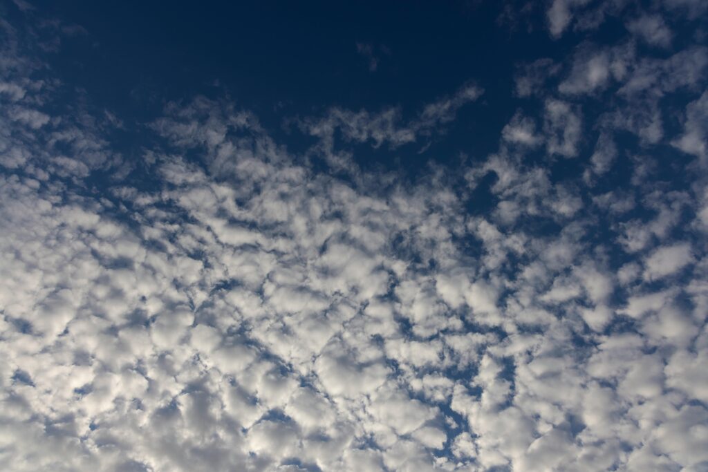 A breathtaking view of cirrocumulus clouds against a deep blue sky at high altitude.