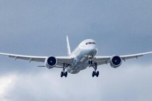 An airplane glides through a cloudy sky during approach and landing.